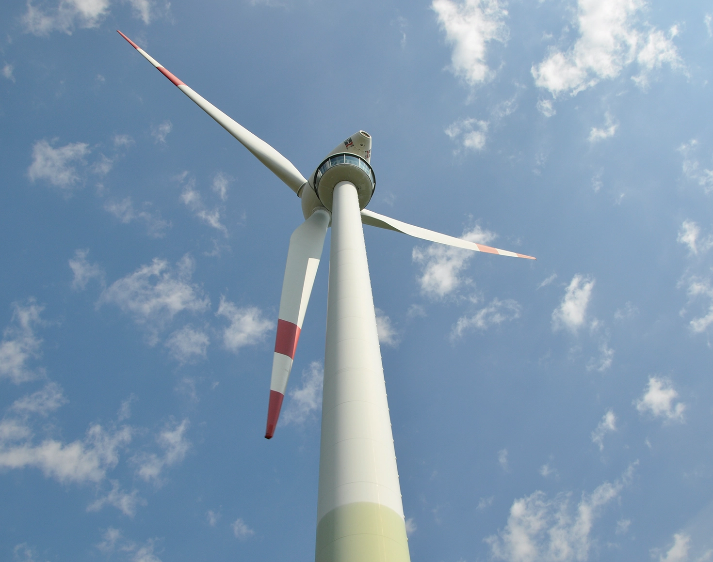 We look down on a wind turbine against a blue sky.